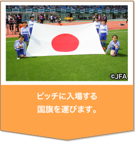 試合前に選手を先導してピッチに入場する国旗を運ぶ。