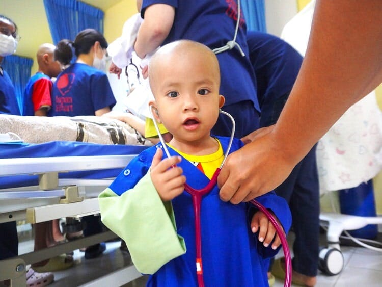 こどもが聴診器を胸に当てる様子